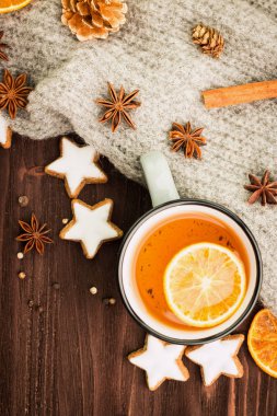 Kış Tema. Noel çay baharat, çay portakal, tarçın, anason, yıldız, biber, çam kozalakları ve ahşap arka plan üzerinde gri eşarp şeklinde kurabiye ile. Yat, yukarıdan görüntüleyin. Metin için yer kopyalayın.