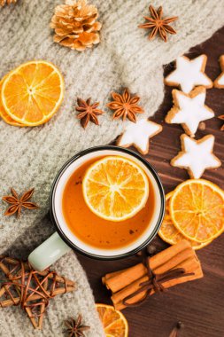 Kış Tema. Noel çay baharat, çay portakal, tarçın, anason, yıldız, biber, çam kozalakları ve ahşap arka plan üzerinde gri eşarp şeklinde kurabiye ile. Yat, yukarıdan görüntüleme.