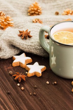 Kış ve yılbaşı tema. Noel çay baharat, çay portakal, tarçın, anason, yıldız, çam kozalakları, biber ve ahşap arka plan üzerinde gri eşarp şeklinde kurabiye ile. Metin için yer kopyalayın.