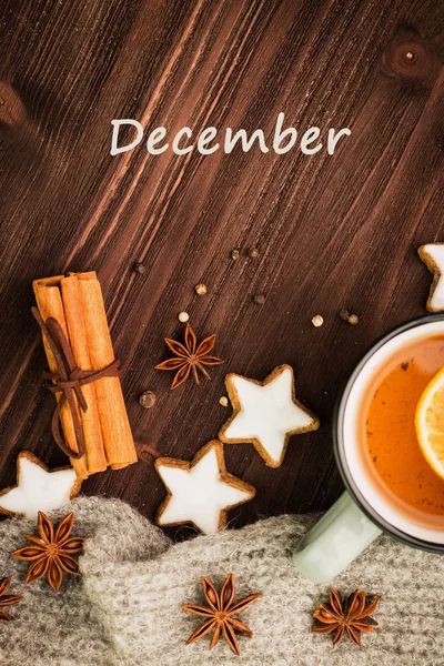 冬のテーマ 熱いお茶とスパイス オレンジ シナモン アニス スター コショウ 木製の背景にグレーのスカーフの形のクッキー フラット レイアウト — ストック写真