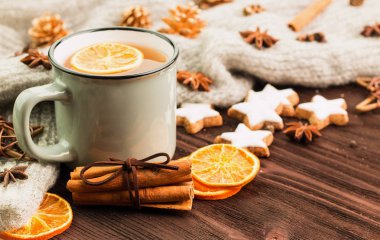 Kış ve yılbaşı tema. Noel çay baharat, çay portakal, tarçın, anason, yıldız, çam kozalakları, biber ve ahşap arka plan üzerinde gri eşarp şeklinde kurabiye ile. Metin için yer kopyalayın.