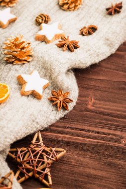 Kış ve yılbaşı tema. Baharatlar, portakal, tarçın, anason, yıldız, biber, ahşap yıldız ve ahşap arka plan üzerinde gri eşarp şeklinde kurabiye. Metin için yer kopyalayın. Yukarıdan görüntüleyin. Düz yatıyordu.