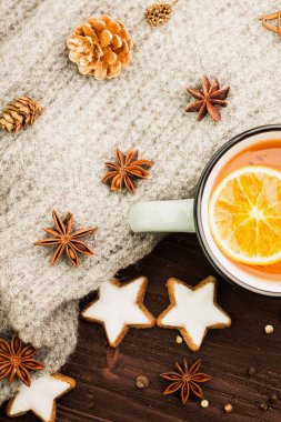 Kış Tema. Noel çay baharat, çay portakal, tarçın, anason, yıldız, biber, çam kozalakları ve ahşap arka plan üzerinde gri eşarp şeklinde kurabiye ile. Yat, yukarıdan görüntüleme.