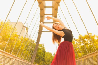 Genç dans ve açık havada siyah gömlek ve tuğla rengi (kırmızı armut) uzun etekli gülümseyen uzun kahverengi saçlı güzel kadın ince. Spor ve sağlıklı kavramı.