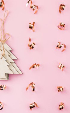 Noel ve yılbaşı şenlikli dekorasyon, ahşap Noel ağaçları pembe bir arka plan üzerinde altın şeritler. Metin için yer kopyalayın. Düz yatıyordu. Yukarıdan görüntülemek.