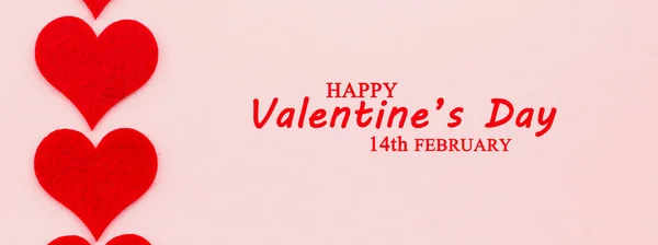 St.Valentine's Day holiday background. Red hearts in a shape of a heart on pink background. Flat lay. View from above with text Happy Valentine's Day and 14th February.