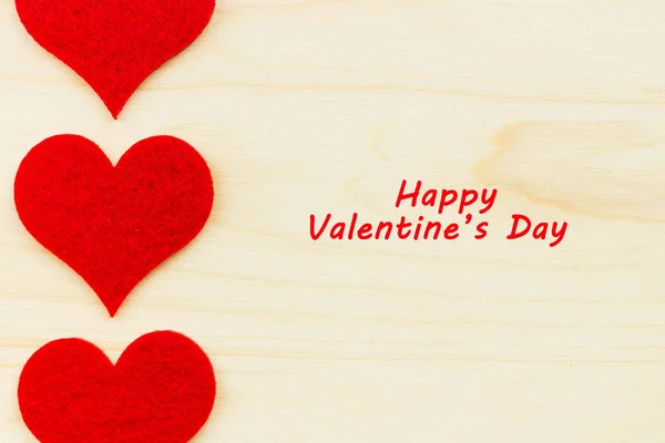 St.Valentine\'s Day holiday background. Red hearts in a shape of a heart on wooden background. Flat lay. View from above with text Happy Valentine\'s Day.
