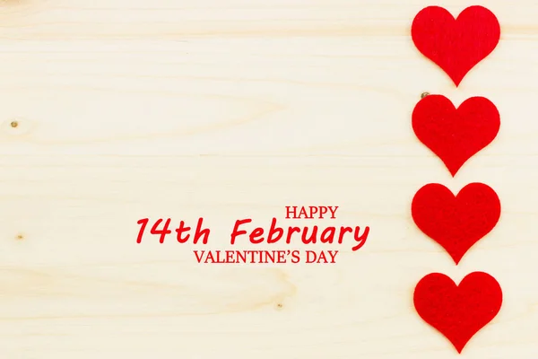 St.Valentine\'s Day holiday background. Red hearts in a shape of a heart on wooden background. Flat lay. View from above with text Happy Valentine\'s Day and 14th February.