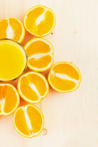 Glass of freshly pressed orange juice with sliced orange halfs on wooden background. Healthy lifestyle concept. Copy space for text. View from above.