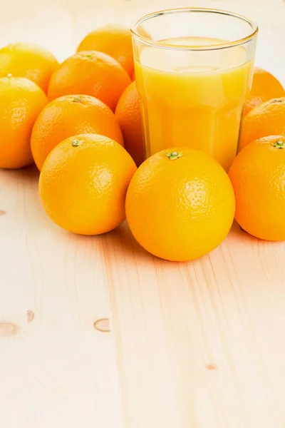 Glass of freshly pressed orange juice with oranges on wooden background. Healthy lifestyle concept. Copy space for text.