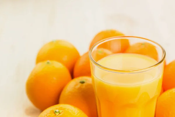 Glass of freshly pressed orange juice with oranges on wooden background. Healthy lifestyle concept. Copy space for text.