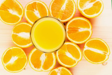 Bardak taze portakal suyu ile ahşap zemin üzerine dilimlenmiş portakal halfs bastırdı. Sağlıklı yaşam konsepti. Yukarıdan görüntülemek.