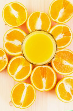 Bardak taze portakal suyu ile ahşap zemin üzerine dilimlenmiş portakal halfs bastırdı. Sağlıklı yaşam konsepti. Yukarıdan görüntülemek.