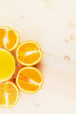 Bardak taze portakal suyu ile ahşap zemin üzerine dilimlenmiş portakal halfs bastırdı. Sağlıklı yaşam konsepti. Metin için yer kopyalayın. Yukarıdan görüntülemek.