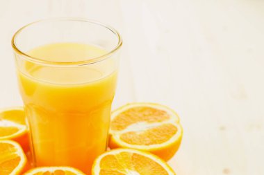 Bardak taze portakal suyu ile ahşap zemin üzerine dilimlenmiş portakal halfs bastırdı. Sağlıklı yaşam konsepti. Metin için yer kopyalayın.