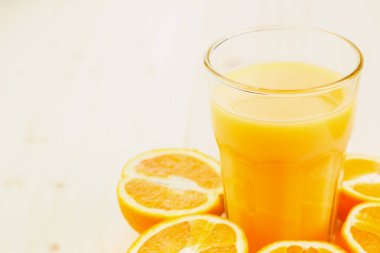 Bardak taze portakal suyu ile ahşap zemin üzerine dilimlenmiş portakal halfs bastırdı. Sağlıklı yaşam konsepti. Metin için yer kopyalayın.