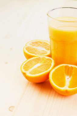 Bardak taze portakal suyu ile ahşap zemin üzerine dilimlenmiş portakal halfs bastırdı. Sağlıklı yaşam konsepti. Metin için yer kopyalayın.