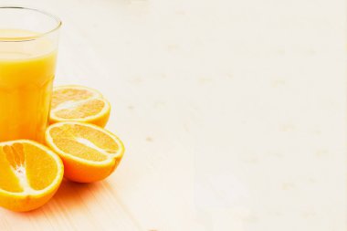 Bardak taze portakal suyu ile ahşap zemin üzerine dilimlenmiş portakal halfs bastırdı. Sağlıklı yaşam konsepti. Metin için yer kopyalayın.