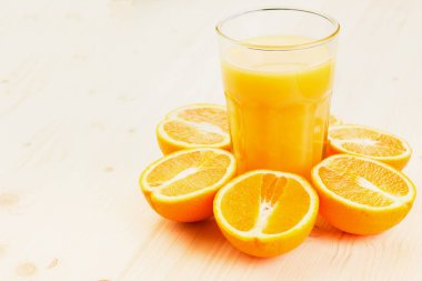 Bardak taze portakal suyu ile ahşap zemin üzerine dilimlenmiş portakal halfs bastırdı. Sağlıklı yaşam konsepti. Metin için yer kopyalayın.