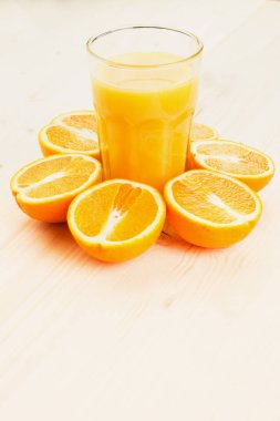 Bardak taze portakal suyu ile ahşap zemin üzerine dilimlenmiş portakal halfs bastırdı. Sağlıklı yaşam konsepti. Metin için yer kopyalayın.