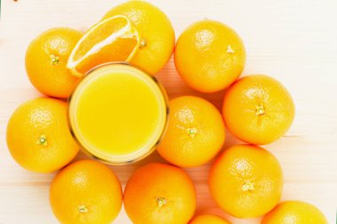 Bardak taze portakal suyu ile portakal preslenmiş ve turuncu bölümü ahşap arka plan üzerine dilimlenmiş. Sağlıklı yaşam konsepti. Yukarıdan görüntülemek.