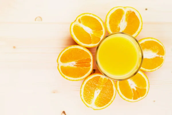 Glass of freshly pressed orange juice with sliced orange halfs on wooden background. Healthy lifestyle concept. Copy space for text. View from above.