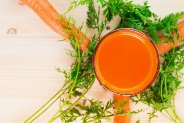 Taze havuç suyu ile havuç ve yeşil havuç tops ahşap masa arka plan üzerinde cam. Sağlıklı yaşam konsepti. Yukarıdan görüntüleyin. Düz yatıyordu. Metin için yer kopyalayın.