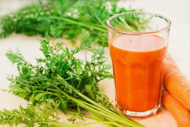 Taze havuç suyu ile havuç ve yeşil havuç tops ahşap masa arka plan üzerinde cam. Sağlıklı yaşam konsepti.