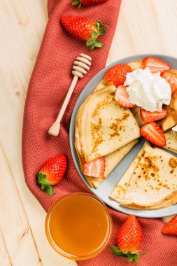 Ev yapımı taze gözlemeler çilek, krem ve ballı ahşap arka plan üzerinde. Yukarıdan görüntülemek.