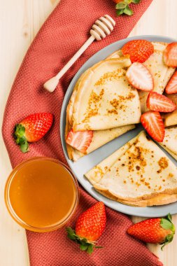 Ev yapımı taze gözlemeler çilek ve ballı ahşap arka plan üzerinde. Yukarıdan görüntülemek. 