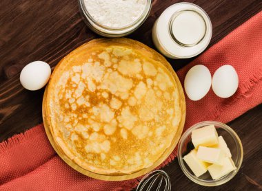 Ev yapımı taze gözlemeler malzemelerle: yumurta, tereyağı, süt ve un rustik ahşap arka plan üzerinde. Üstten görünüm.