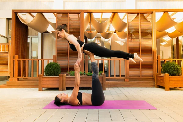 两个年轻的妇女练习阿克罗瑜伽户外 阿克罗瑜伽阿萨纳鸟的腿摆姿势 健康和运动理念 — 图库照片