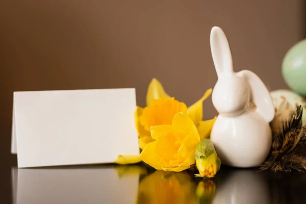Pequena estatueta de coelho branco com ovos de páscoa e narciso — Fotografia de Stock