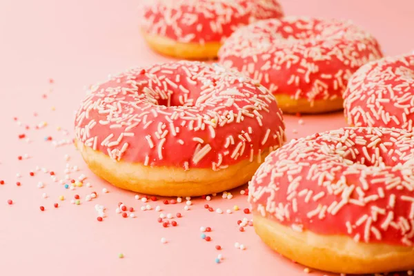 珊瑚甜甜圈。在粉红色背景上装饰有糖霜的甜甜圈. — 图库照片