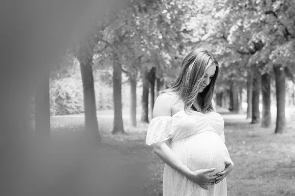 Счастливая беременная женщина позирует на зеленом естественном фоне — стоковое фото