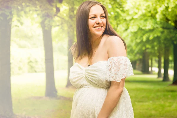 Felice donna incinta posa su sfondo verde naturale — Foto Stock