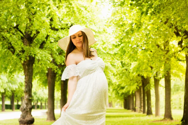 Felice donna incinta posa su sfondo verde naturale — Foto Stock