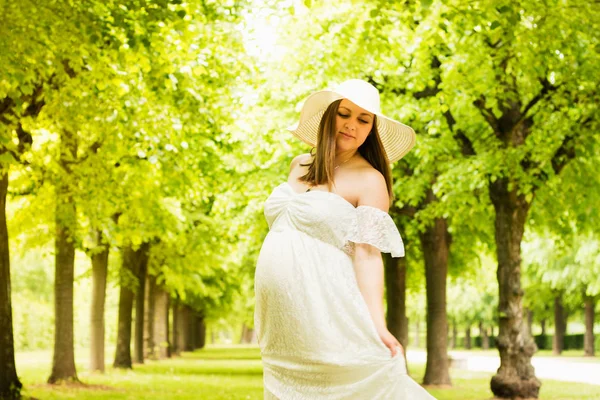 Mujer embarazada feliz posando sobre fondo verde natural —  Fotos de Stock