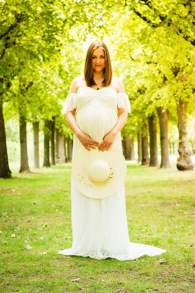 Feliz mulher grávida posando sobre fundo natural verde — Fotografia de Stock
