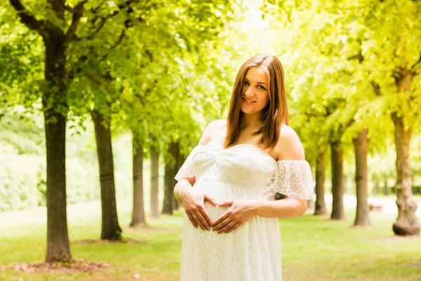 Gelukkige zwangere vrouw poseren over groene natuurlijke achtergrond — Stockfoto