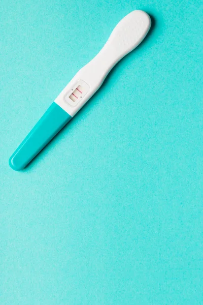 Positive blue plastic pregnancy test on blue background.