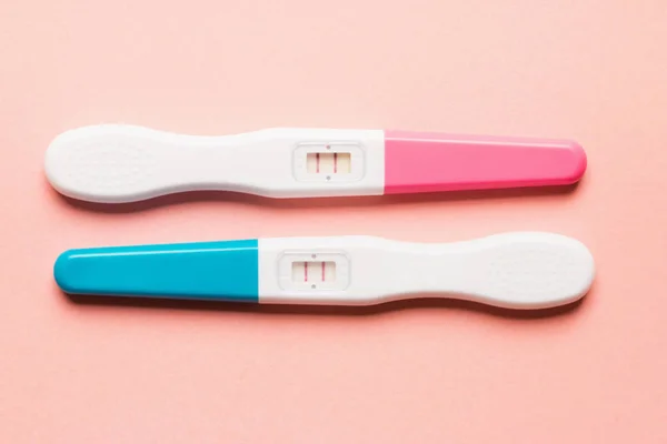 Θετικό ροζ και μπλε πλαστικό τεστ εγκυμοσύνης σε ροζ φόντο — Φωτογραφία Αρχείου