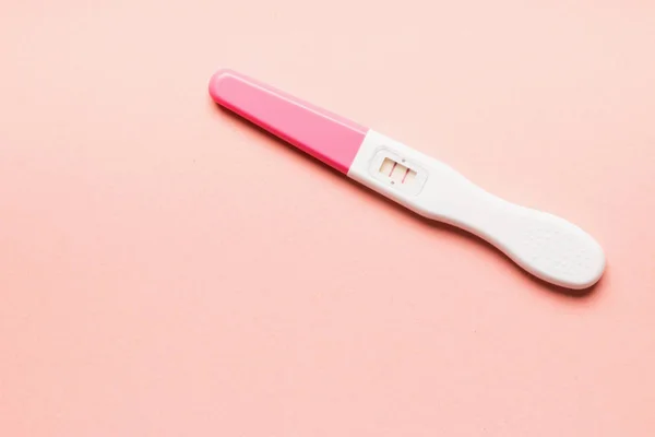 Teste de gravidez de plástico rosa positivo em fundo rosa . — Fotografia de Stock