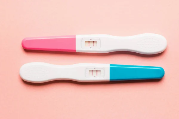 Positive pink and blue plastic pregnancy test on pink background Stock Photo