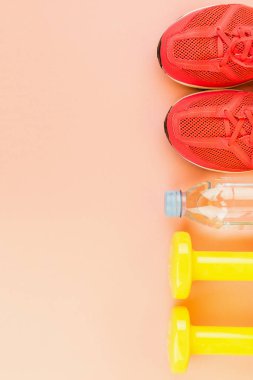 Sarı halter, bir şişe tatlı su ve pembe spor ayakkabılar.