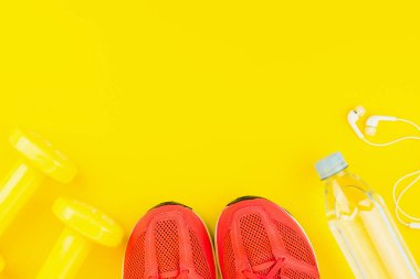 Beyaz kulaklıklar, sarı halterler, bir şişe tatlı su