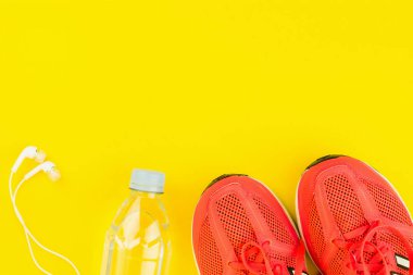 Beyaz kulaklıklar, bir şişe tatlı su ve pembe spor ayakkabılar