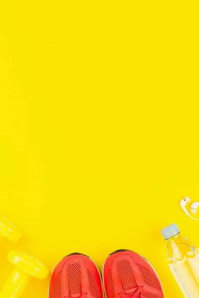 Witte koptelefoon, gele dumbbells, een fles zoet water Stockfoto