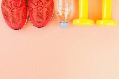 Sarı halter, bir şişe tatlı su ve pembe spor ayakkabılar.