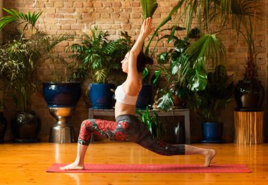 Stüdyoda yoga yapan genç bir kadın. Kırmızı mat üzerinde kalmak